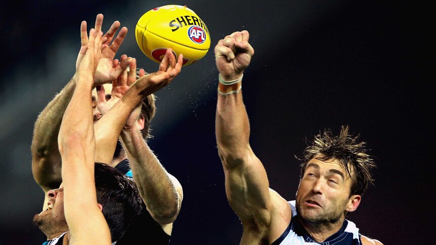 Corey Enright of the Cats attempts to spoil the ball