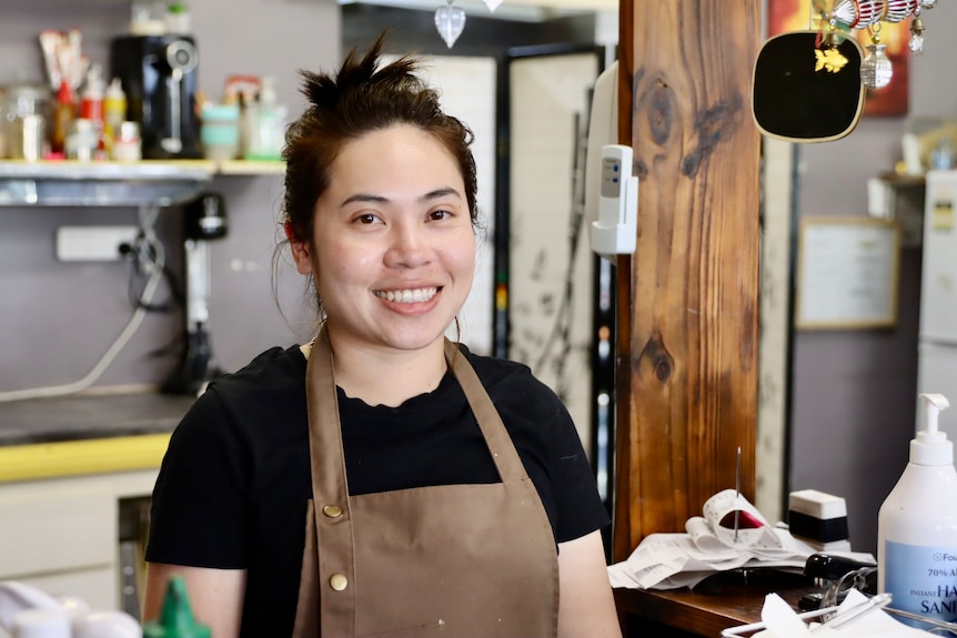 A female cafe worker standing behind a counter.  