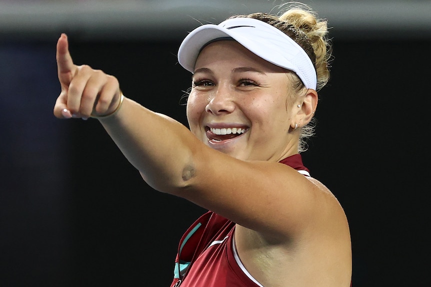 An American female tennis player points with her right hand as she celebrates victory.