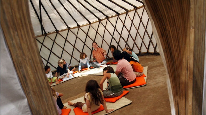 Children sit on the floor in a circle with their teacher