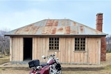 A newly rebuilt timber hut with a motorbike outfront