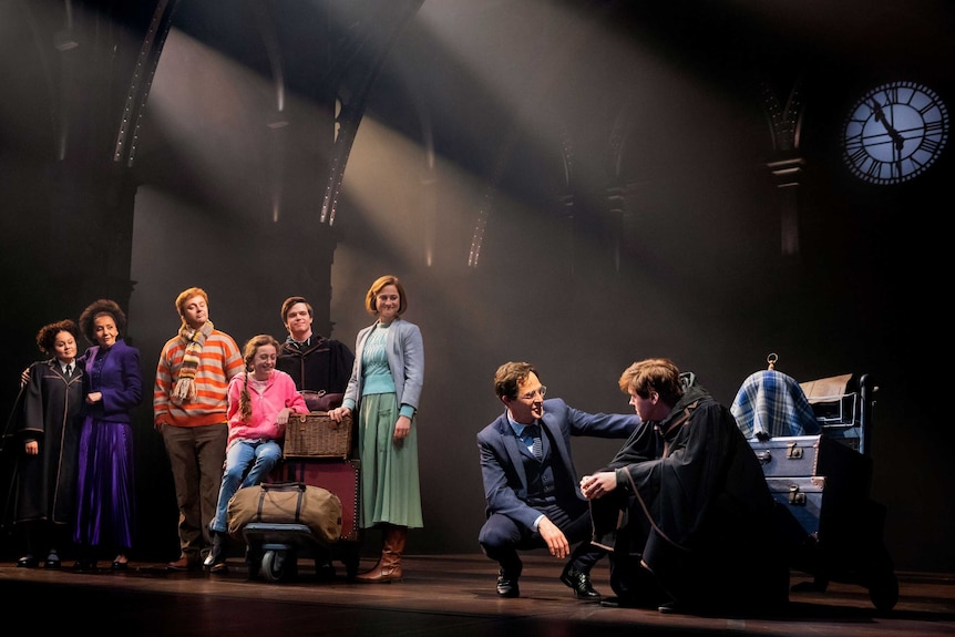 A group of performers dressed as wizards on stage, a family observing a father and son talking