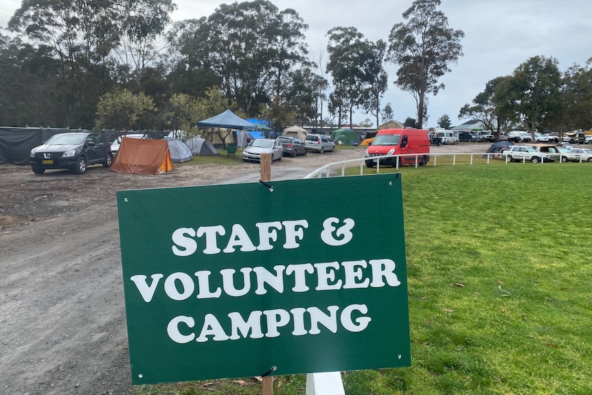 Sign for volunteer campground with tents in the background