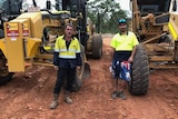 two construction workers in front of excavators