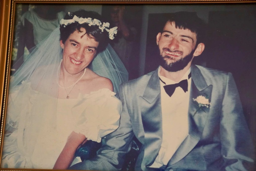 An old wedding photo shows a younger Jenni and David in their wheelchairs.