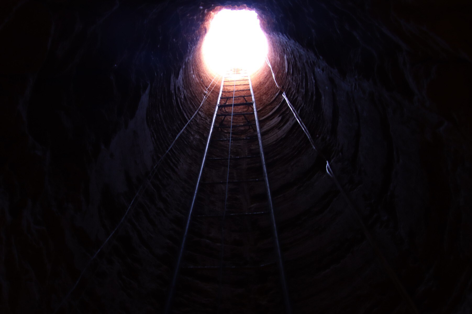 Looking up a ladder to the top of an underground mine. 