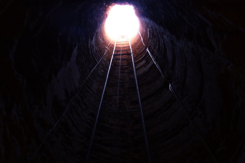 Looking up a ladder to the top of an underground mine. 