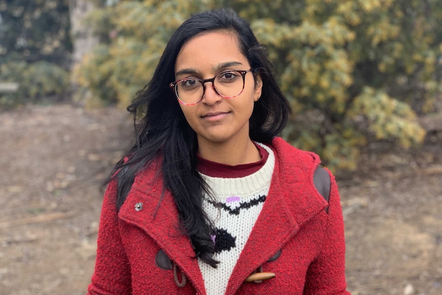 Zoya, wearing a red jacket, looks into the camera.