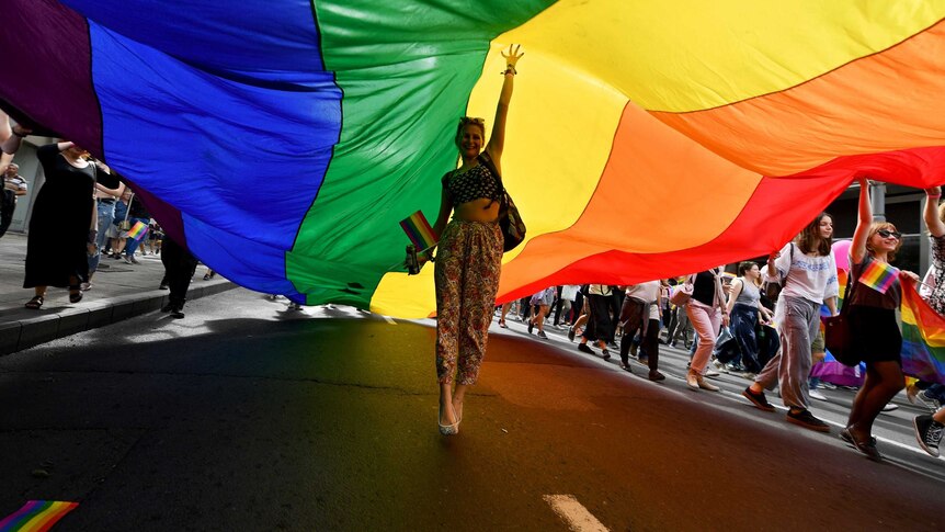 A woman walks under a rainbow flag