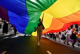 A woman walks under a rainbow flag