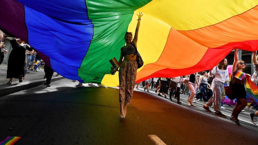 A woman walks under a rainbow flag