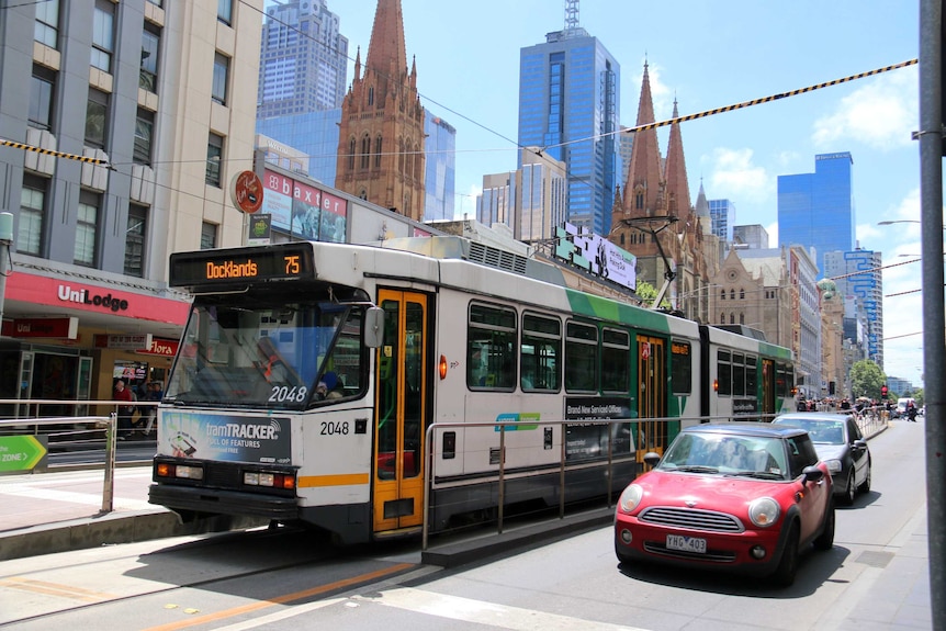 A number 75 tram travels along Flinders Street in Melbourne's CBD