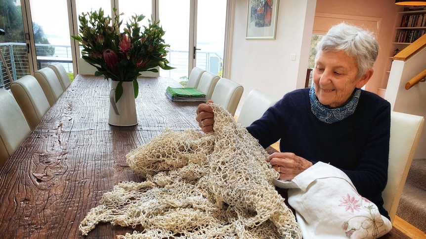 Pam Thorne sits at a table with her hand-knitted shroud made from recycled paper