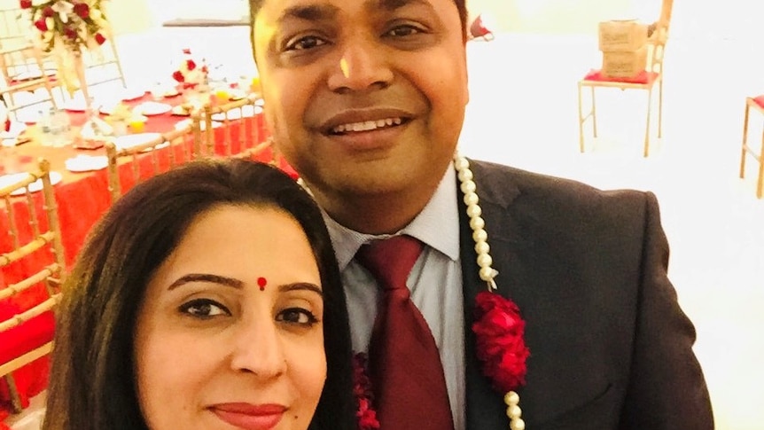 Shivani Sharma wears a red dress and takes a selfie with Vibhav Sharma, who is in a black suit.