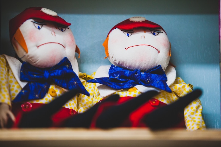 Two cloth dolls on a shelf at haberdashery