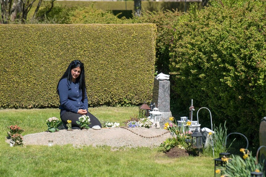 Mirrey Gourie kneels at her father's grave.