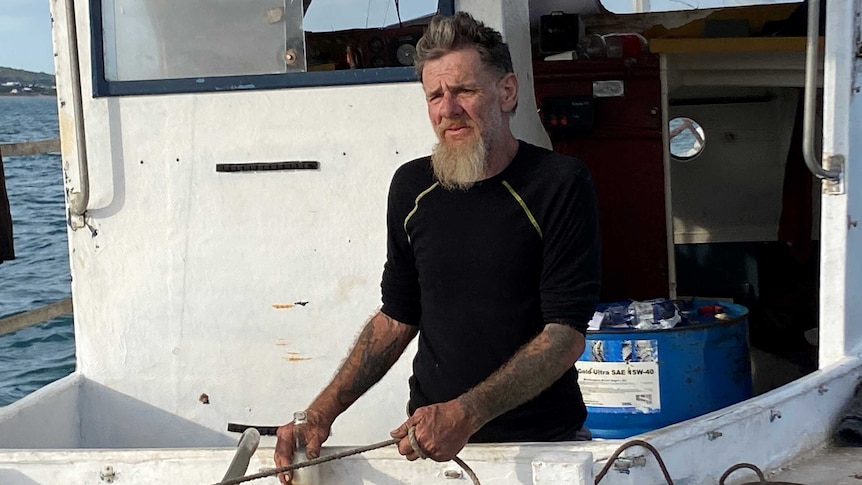 A man with a beard and grey hair on an old boat