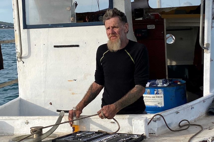 A man with a beard and grey hair on an old boat