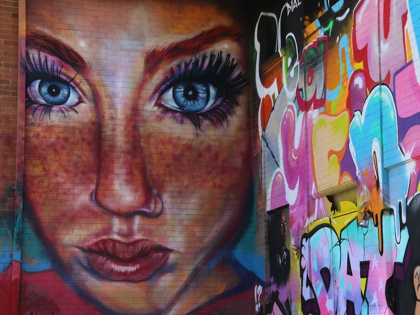 Bright murals on the walls, including a bit face with giant eyes and long lashes.
