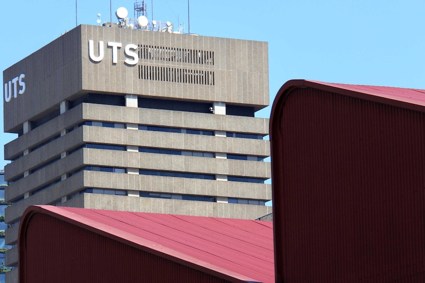 The top of UTS Tower visible over red corrugated rooves of a warehouse.