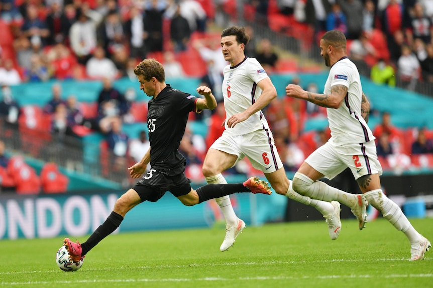 Thomas Mueller shoots with two English players trailing him.