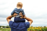 Man with a toddler on his shoulders looks toward the ocean for a story about male infertility and sperm count