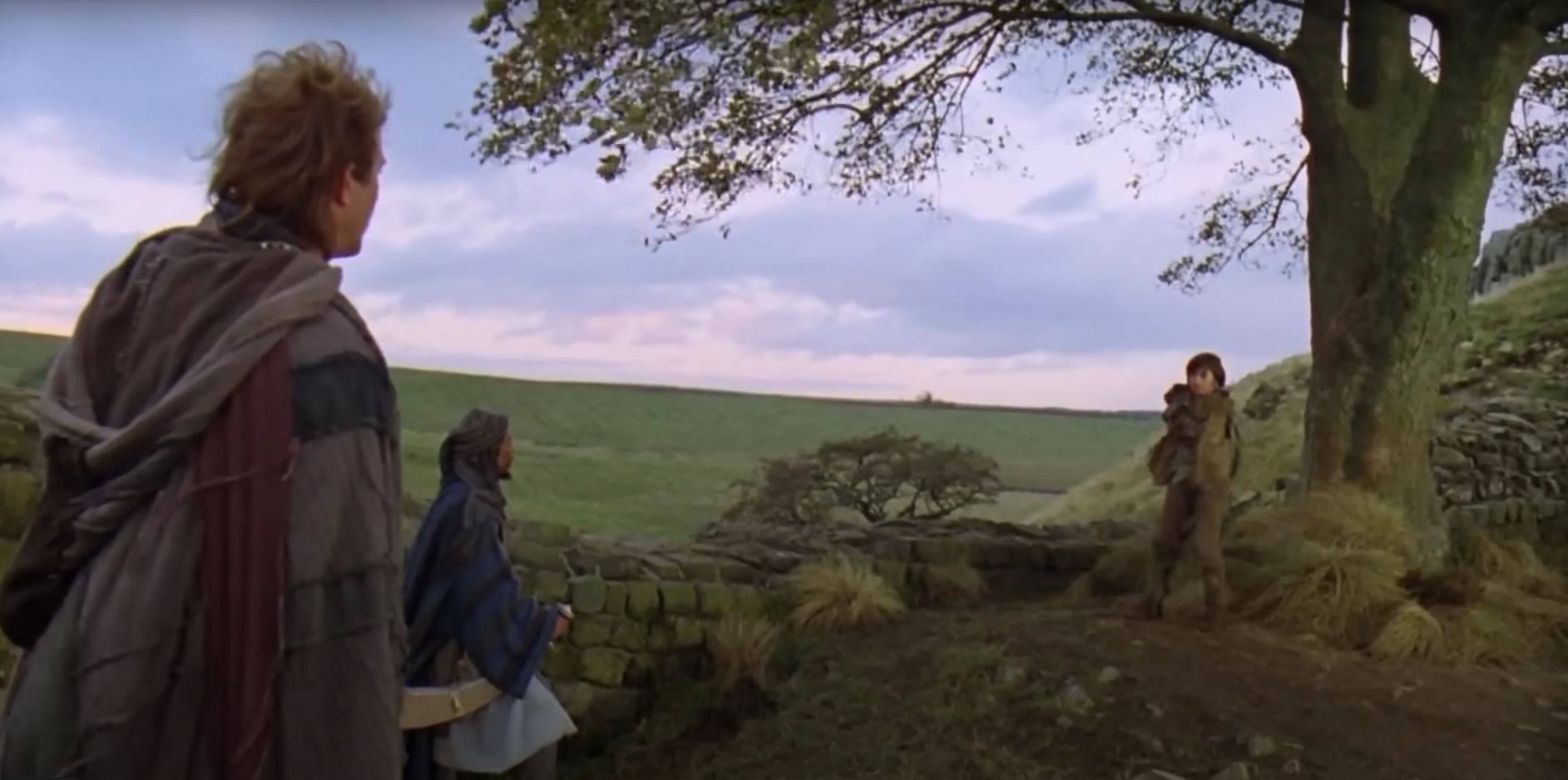 Two men in costume, kevin costner and morgan freeman talk to a little boy standing in front of the tree 