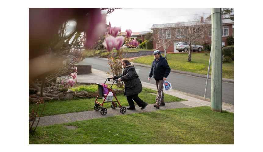 Two people walk up the footpath to the front door of their house.