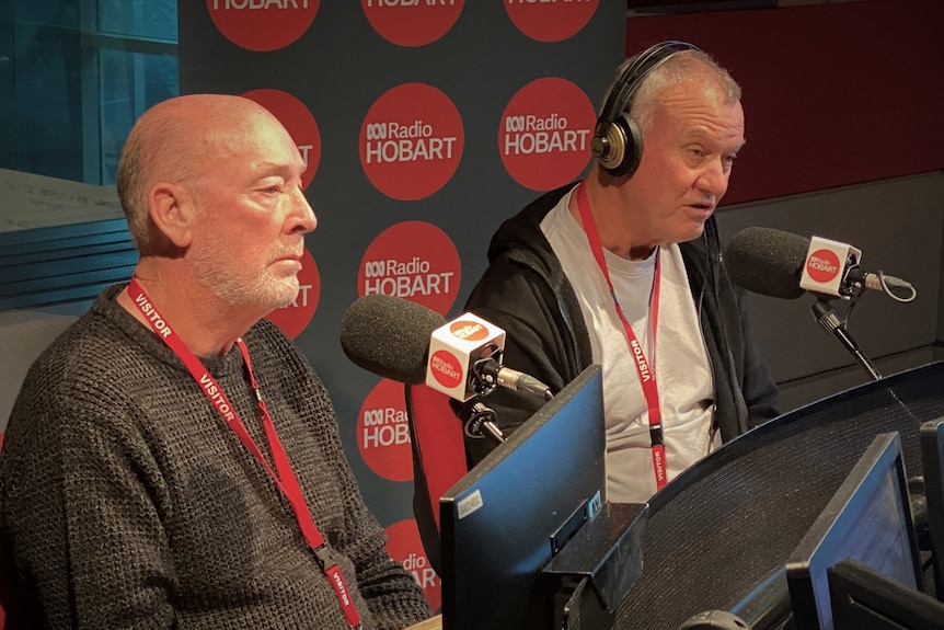 Two men, one wearing headphones, sit in front of microphones and ABC Radio Hobart logos.