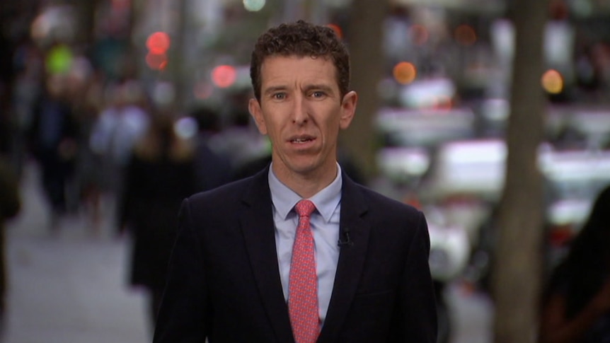 Medium shot of Ziffer looking to camera with blurred cars and street in background.