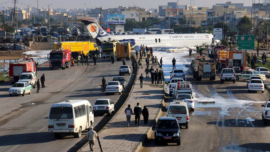 Cars and trucks back up on a motor way as a Caspian Airways  plane sits on the road after performing an improvised landing