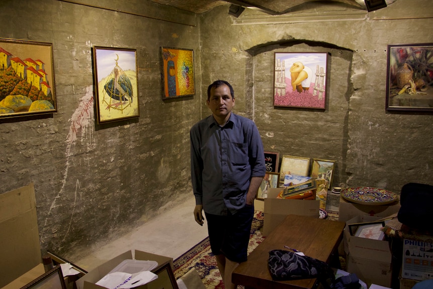 Crimean Tatar Erfan Kudusov stands in his art gallery, surrounded by paintings by his people.