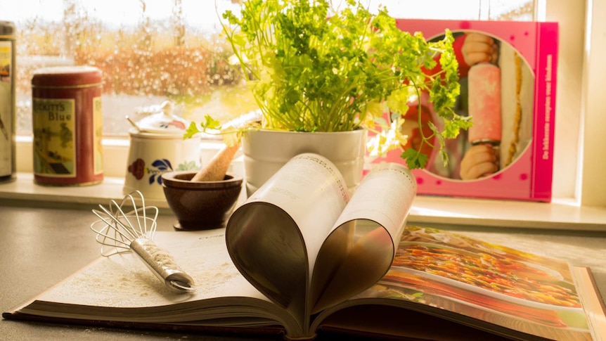 Cookbook lying on kitchen counter and surrounded by kitchen utensils for the Buying Hope episode of the Head Room podcast.