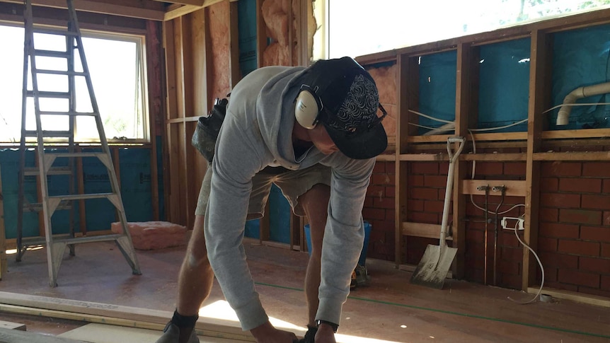 Building apprentice cuts timber.
