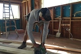Building apprentice cuts timber.