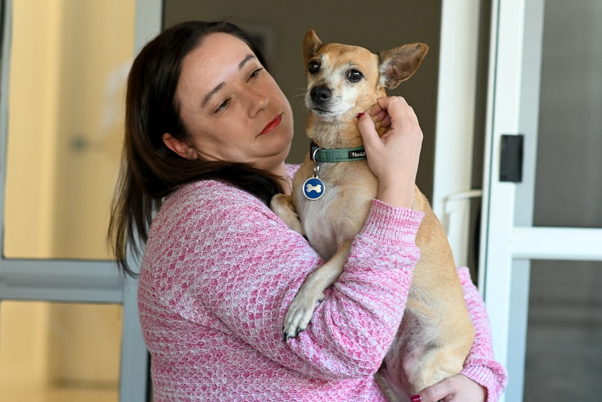 Woman with dark hair holding small dog