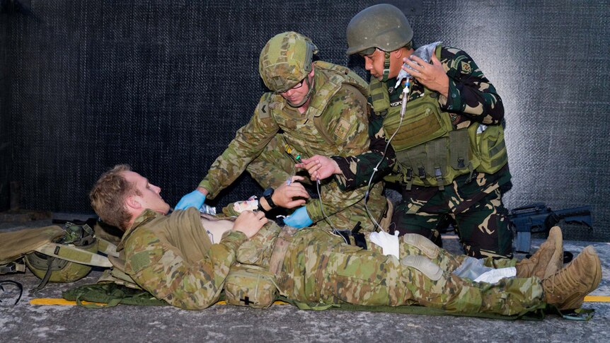 An Australian soldier and a Filipino soldier provide medical care during an urban combat skills demonstration.