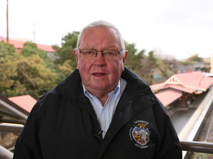 Older man with glasses, grey short hair and puffer jacket