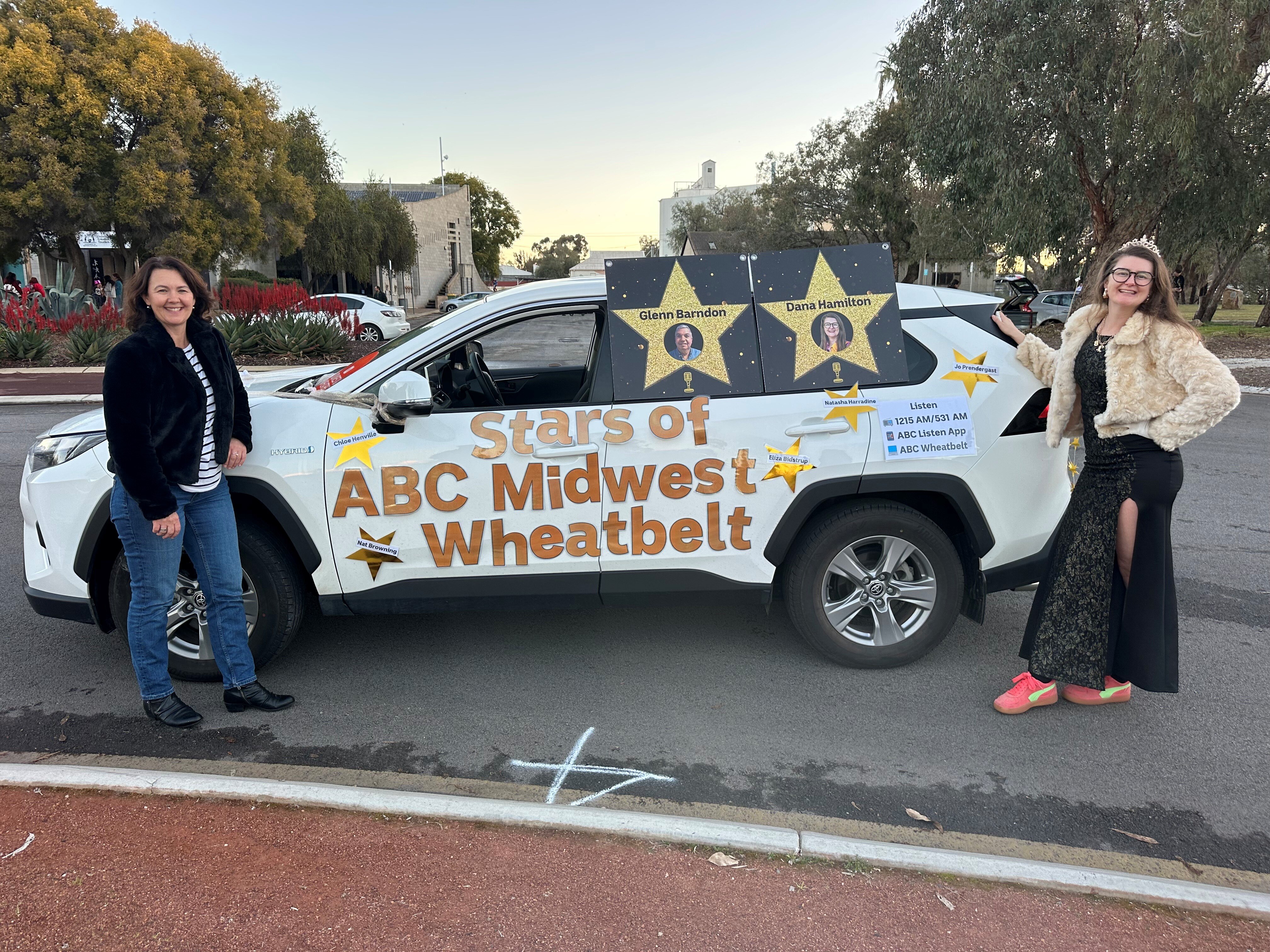 Two women stand beside a car decorated with stars, reading Stars Of ABC Midwest Wheatbelt 