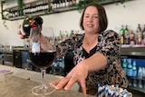 Emily Blades stands behind the bar and pours a glass of red wine.