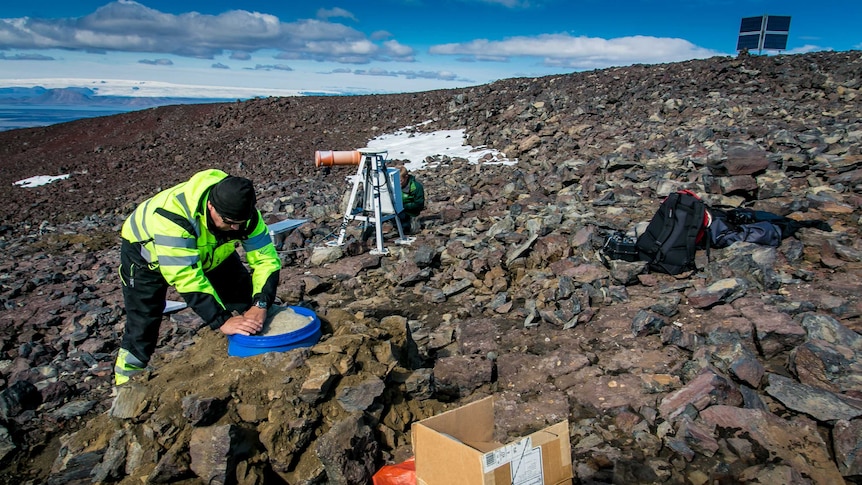 Scientist on rocky hill with equipment