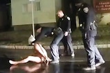 A Rochester police officer puts a hood over the head of Daniel Prude as he sits on the ground naked.