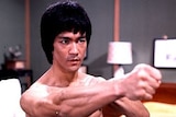 A shirtless Bruce Lee throws a punch