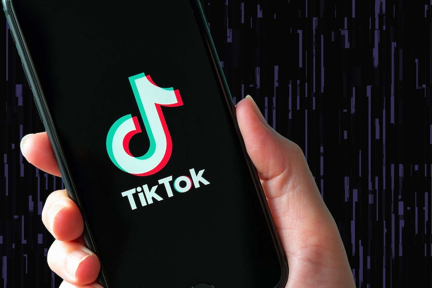 A person holds a smartphone with the TikTok logo on it.