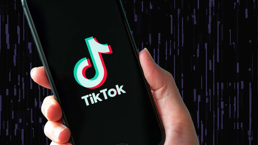 A person holds a smartphone with the TikTok logo on it.
