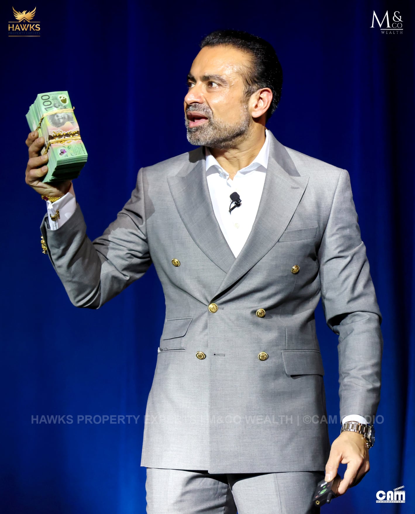 A man holding a huge wad of hundred dollar notes while giving a speech.