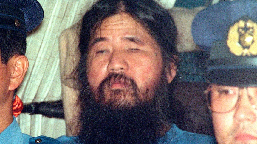 Doomsday cult leader Shoko Asahara, center, sits in a police van following an interrogation