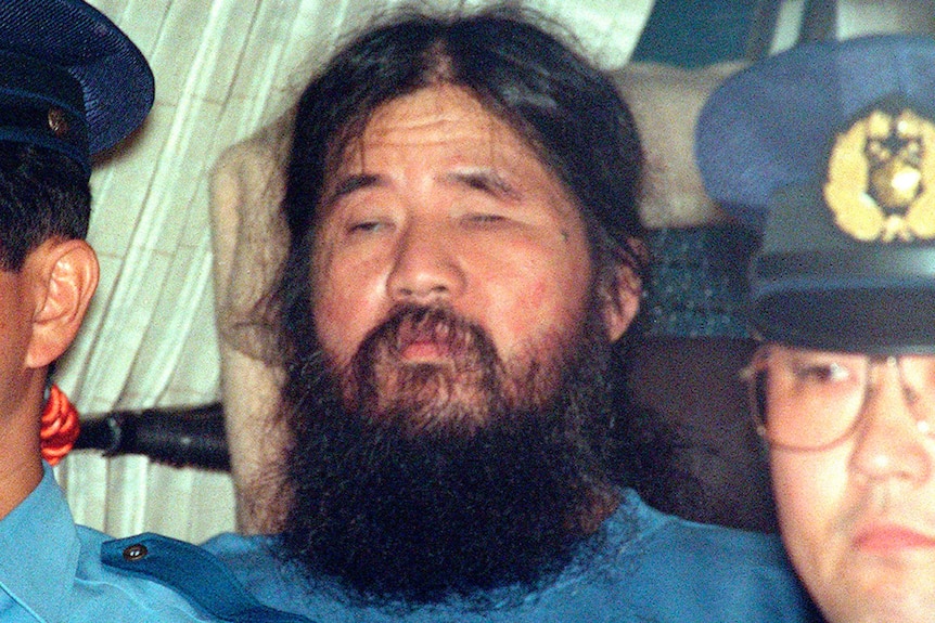 Doomsday cult leader Shoko Asahara, center, sits in a police van following an interrogation