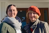 A woman wearing an organge beret with a younger woman wearing a grey scarf.