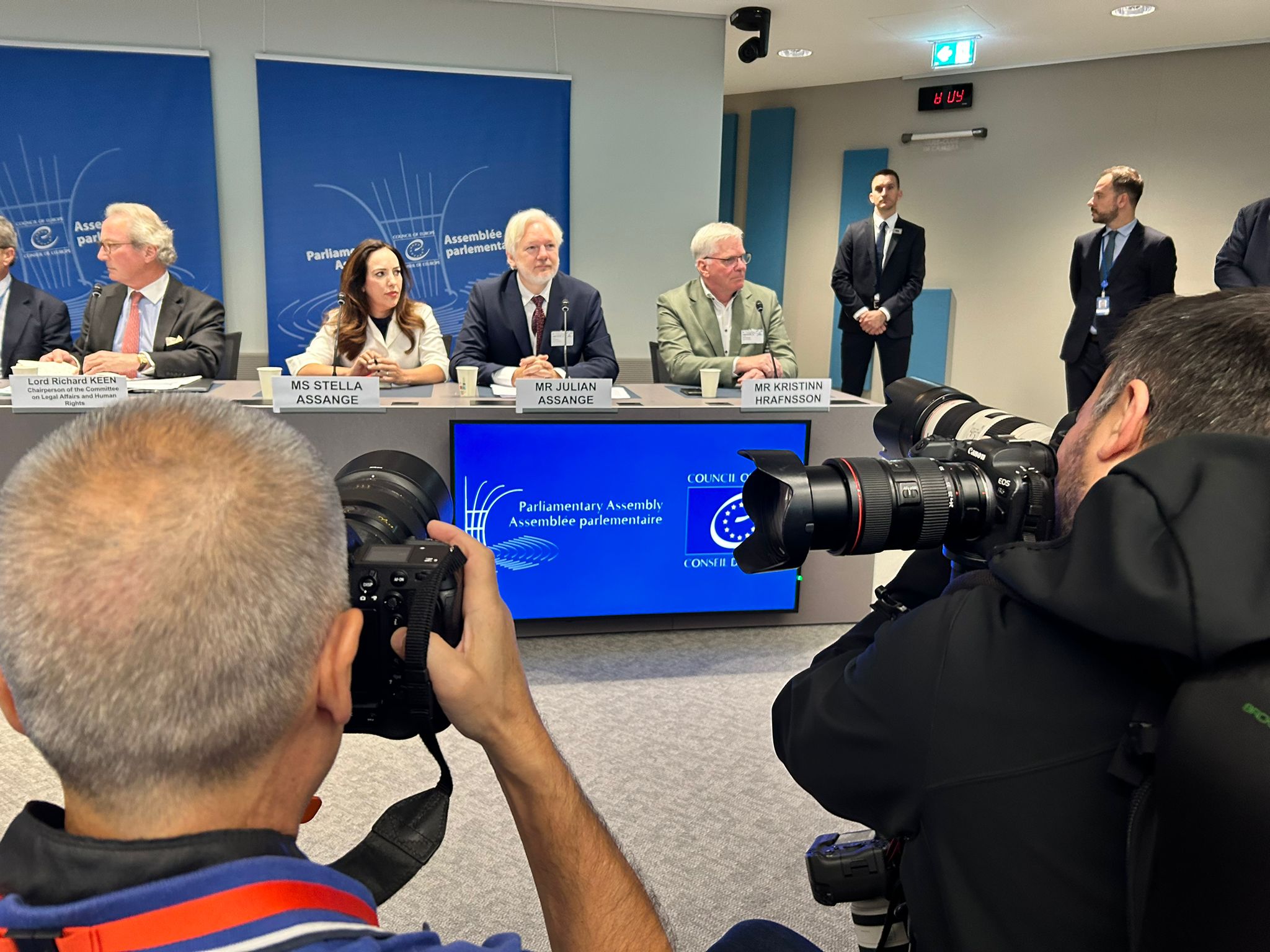 Julian Assange sitting in front of photographers. 